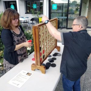 2 personnes qui jouent au puissance quatre géant disposé sur une table