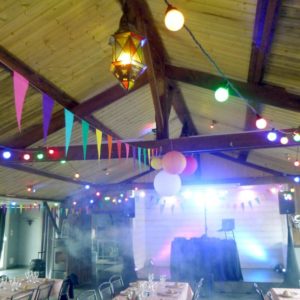 Guirlandes guinguette et fanions de couleurs dans une salle avec charpente en bois