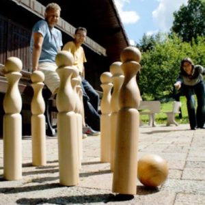 Groupe de personnes jouant aux quilles bowling en bois sur une terrasse